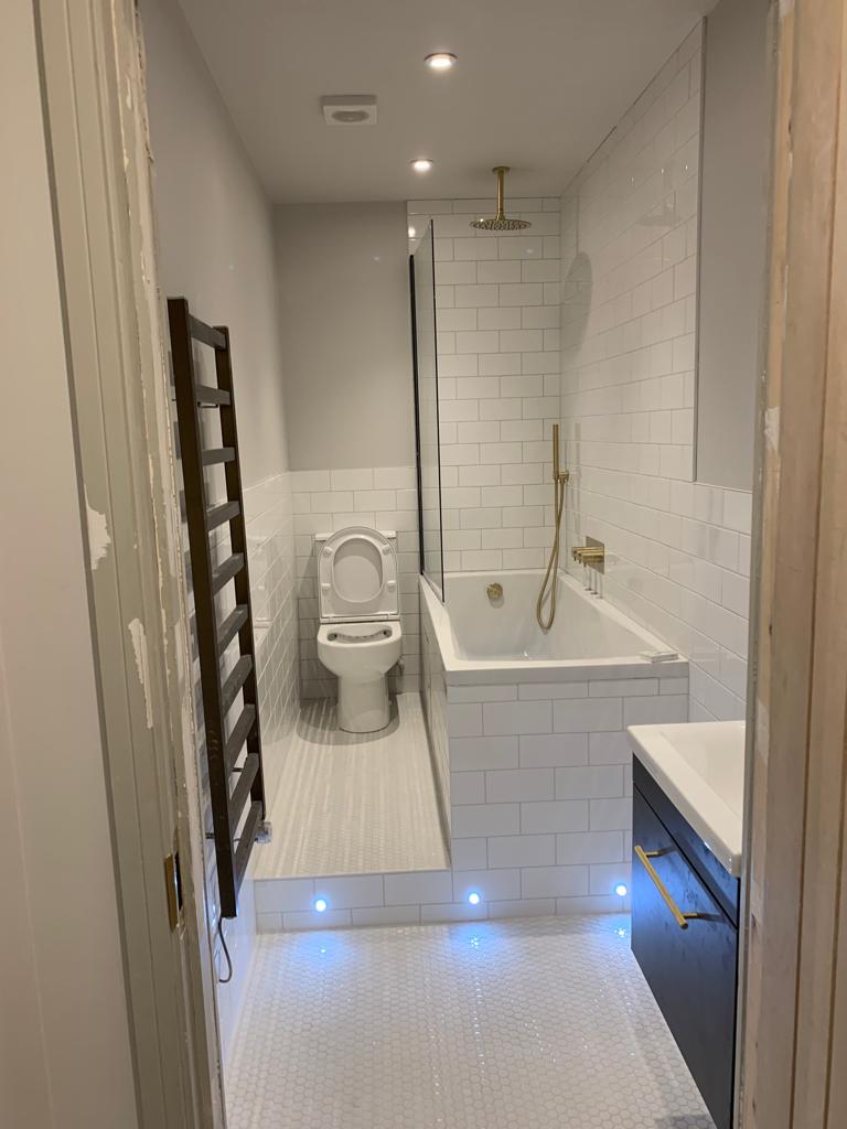 Bathroom white tiling bath gold fittings